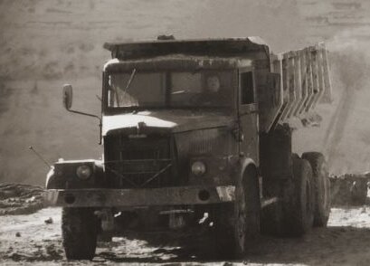 Vintage dump truck in a sand pit, photographed in sepia tones, symbolizing early sand extraction work.