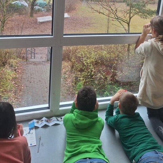 Children looking outside through a large window