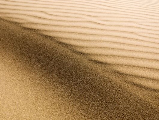 Fine desert sand with wavy patterns formed by the wind.