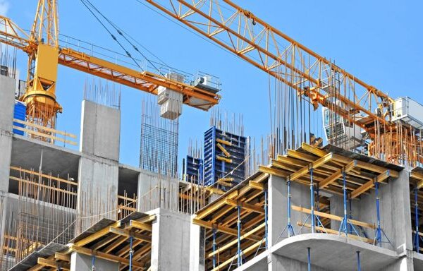 Construction site with a large yellow crane and a concrete building under construction, symbolizing the use of building sand.