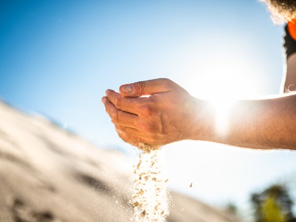 Hands letting sand run through fingers in sunlight