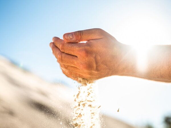 Hands letting sand run through fingers in sunlight